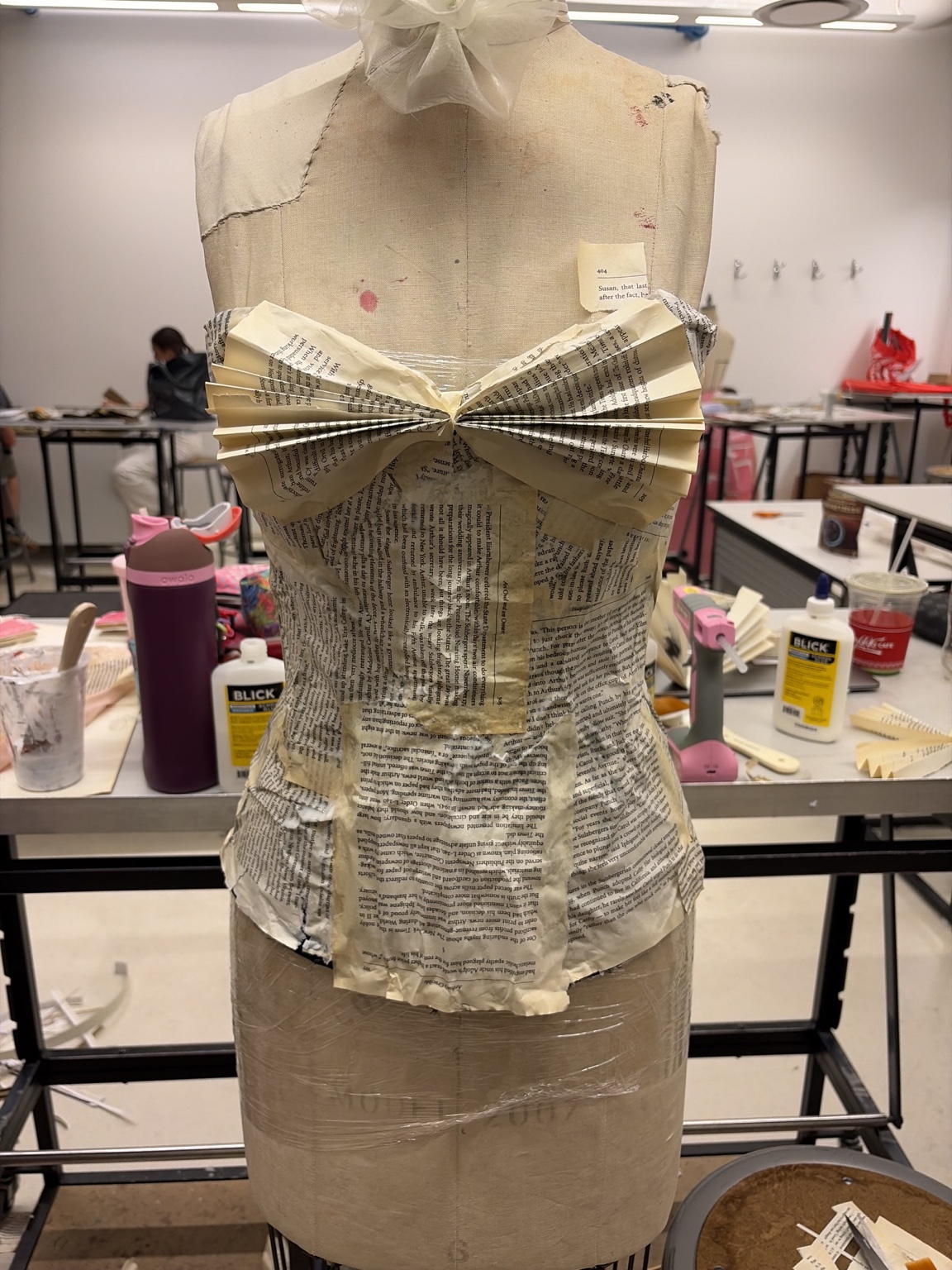 Close-up of pleated book pages forming the garment bodice